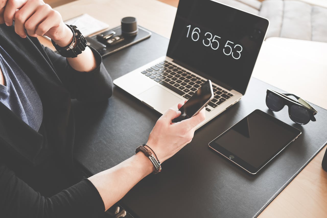 A modern workspace featuring a laptop, smartphone, tablet, and sunglasses, illustrating digital connectivity.